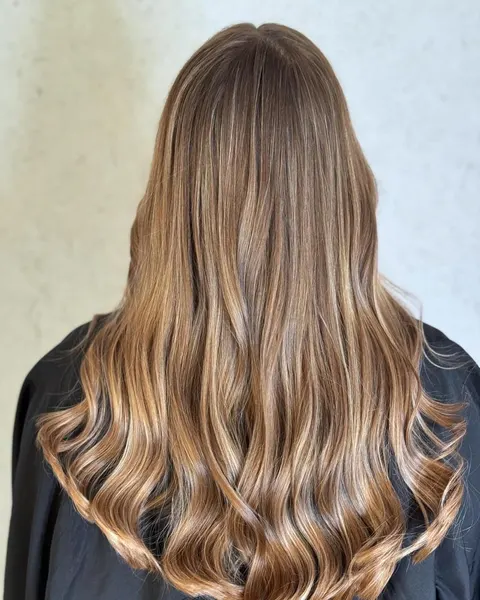 Langes Braun mit warmem Karamell-Balayage in Wellen, von hinten