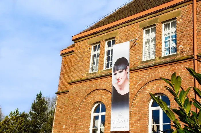 Die ehemalige Kirche aus Backstein, in der der Salon liegt, von außen mit Viano-Banner