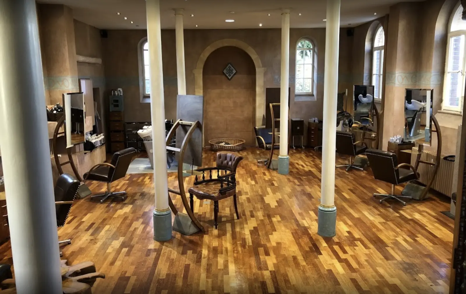 Der Salon in der ehemaligen Kirche: Holzboden, Säulen, hohe Rundbogenfenster und Bedienplätze